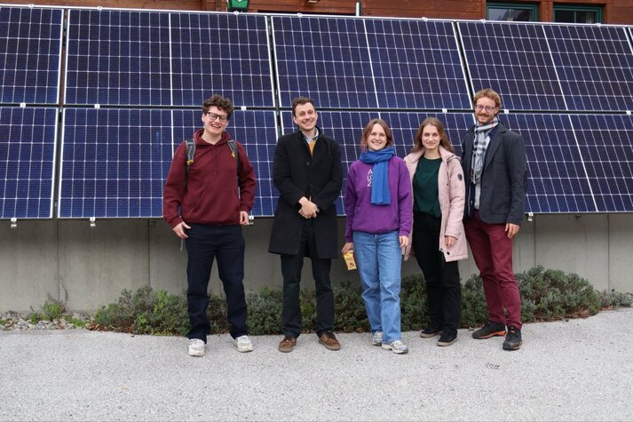A group of friends on a study visit standing in front of a solar array