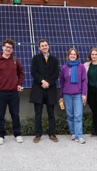 A group of friends on a study visit standing in front of a solar array